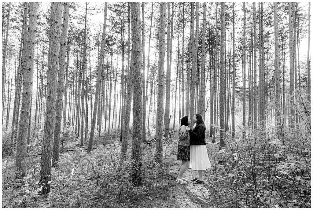 Happy engaged couple standing in tall pines forest at Townsend Park